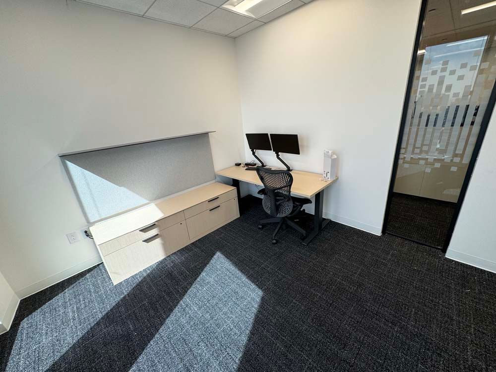 A small office with a desk and two monitors.