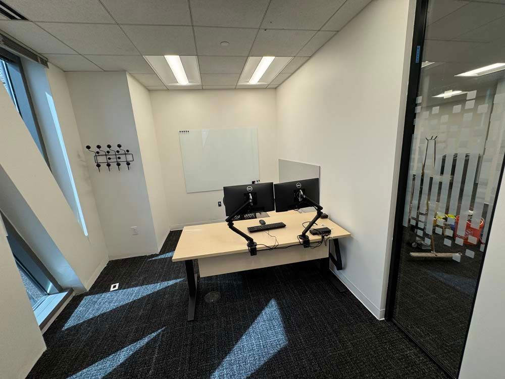 A small office with two desks and two monitors.