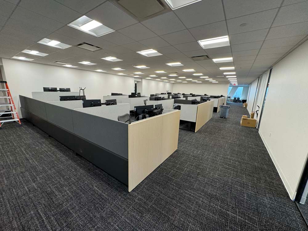 A large office with a lot of cubicles and a ladder.