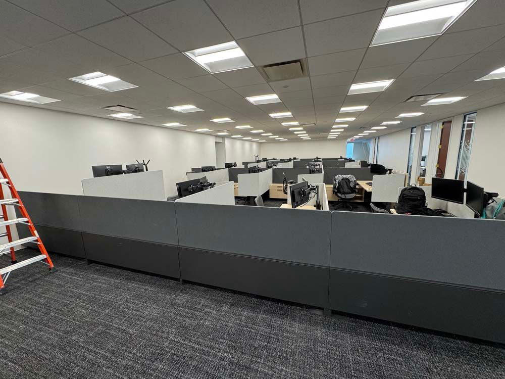 A large office with a lot of cubicles and a ladder.