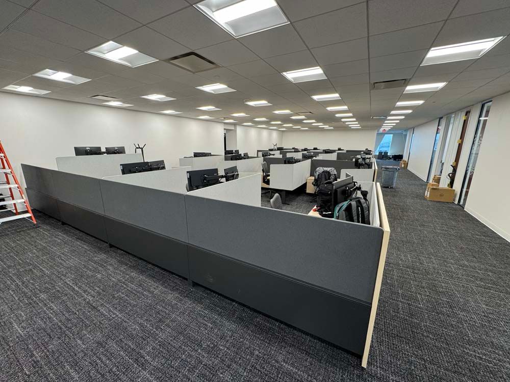 A large office with a lot of cubicles and a ladder.