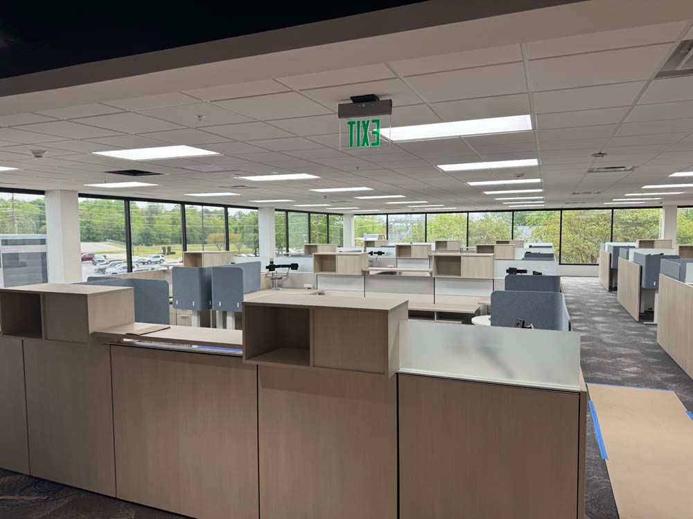 A large office with lots of cubicles and a green exit sign.