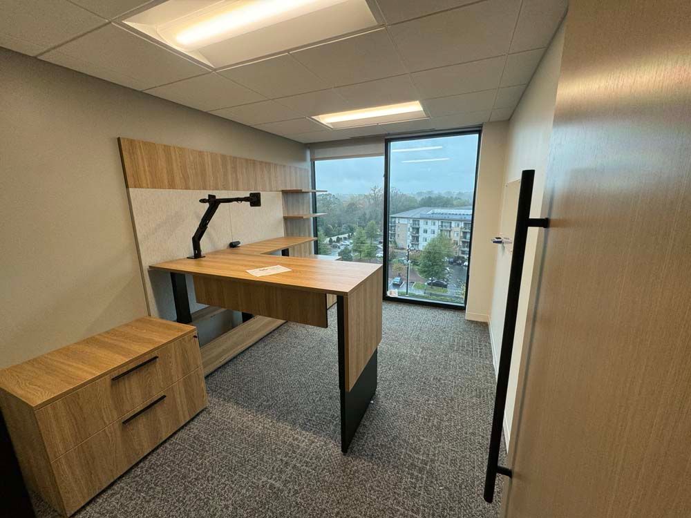 A small office with a standing desk and a large window.