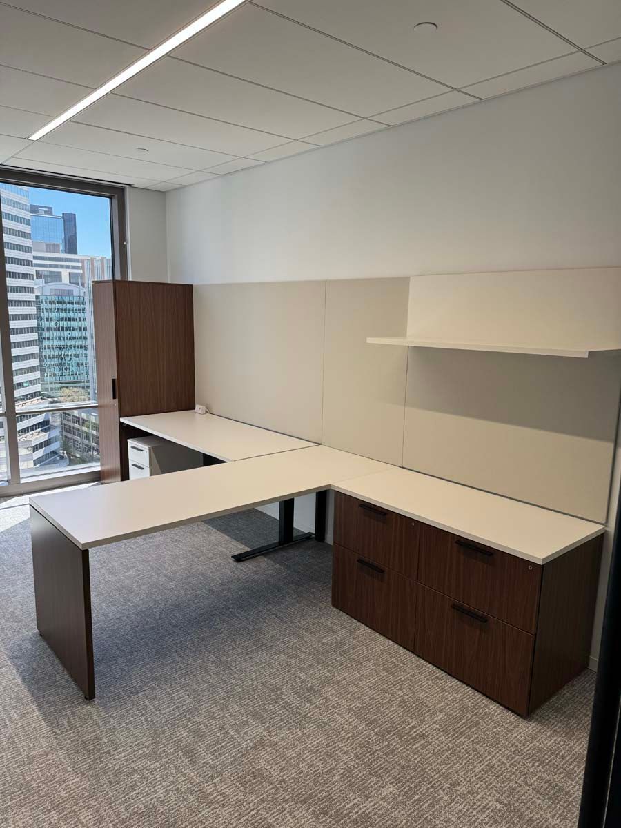 There is a desk in the middle of the room with a window.