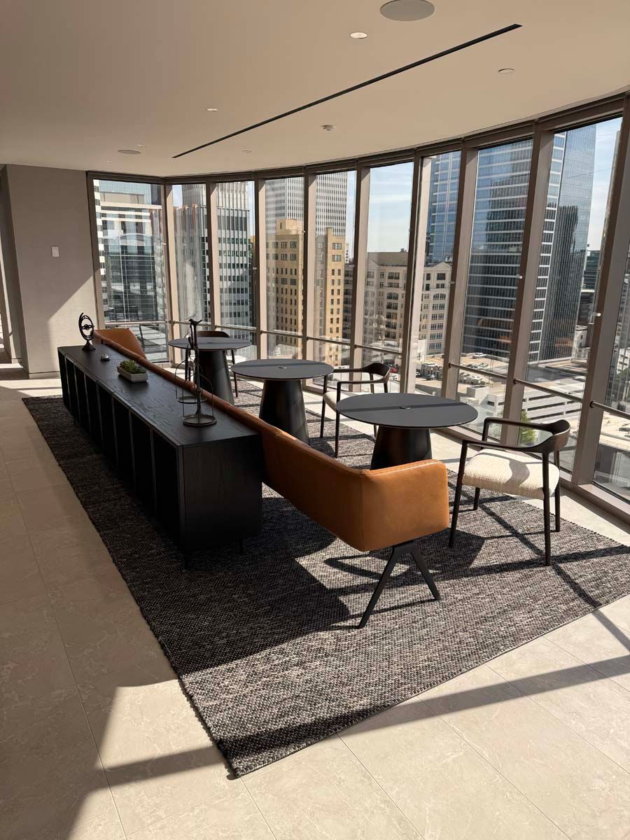 A room with tables and chairs in front of a large window.