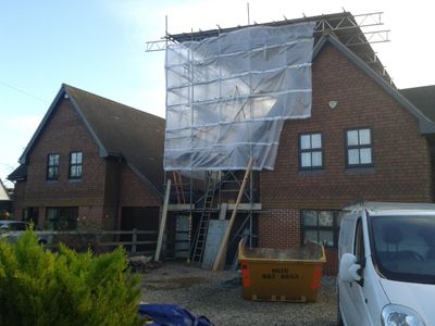 Scaffolding under protective sheeting on the front of a house