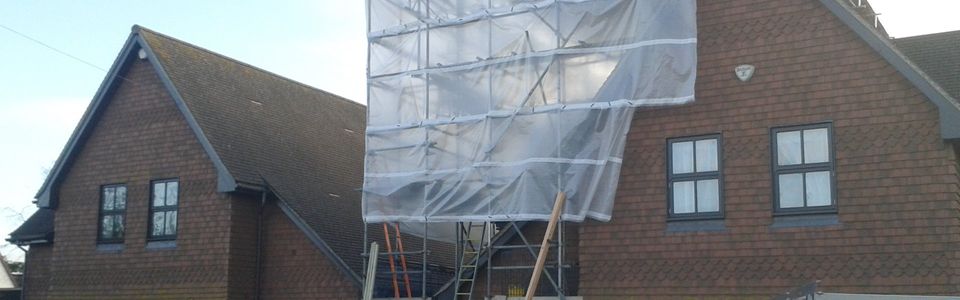 Scaffolding on the side of a house, covered by protective sheeting
