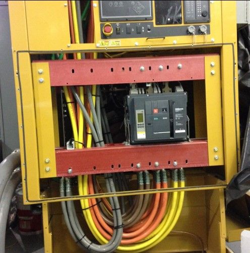 Yellow and red electrical panel with wires and circuit breakers.