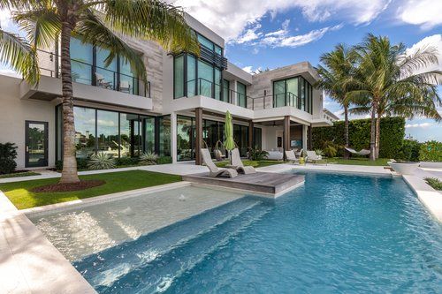 Beautiful backyard infinity pool with ledge and fountains in modern, waterfront Boca Raton luxury home