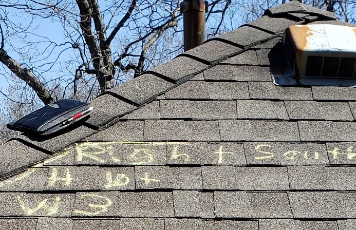 Asphalt shingle roof being inspected for potential wind damage