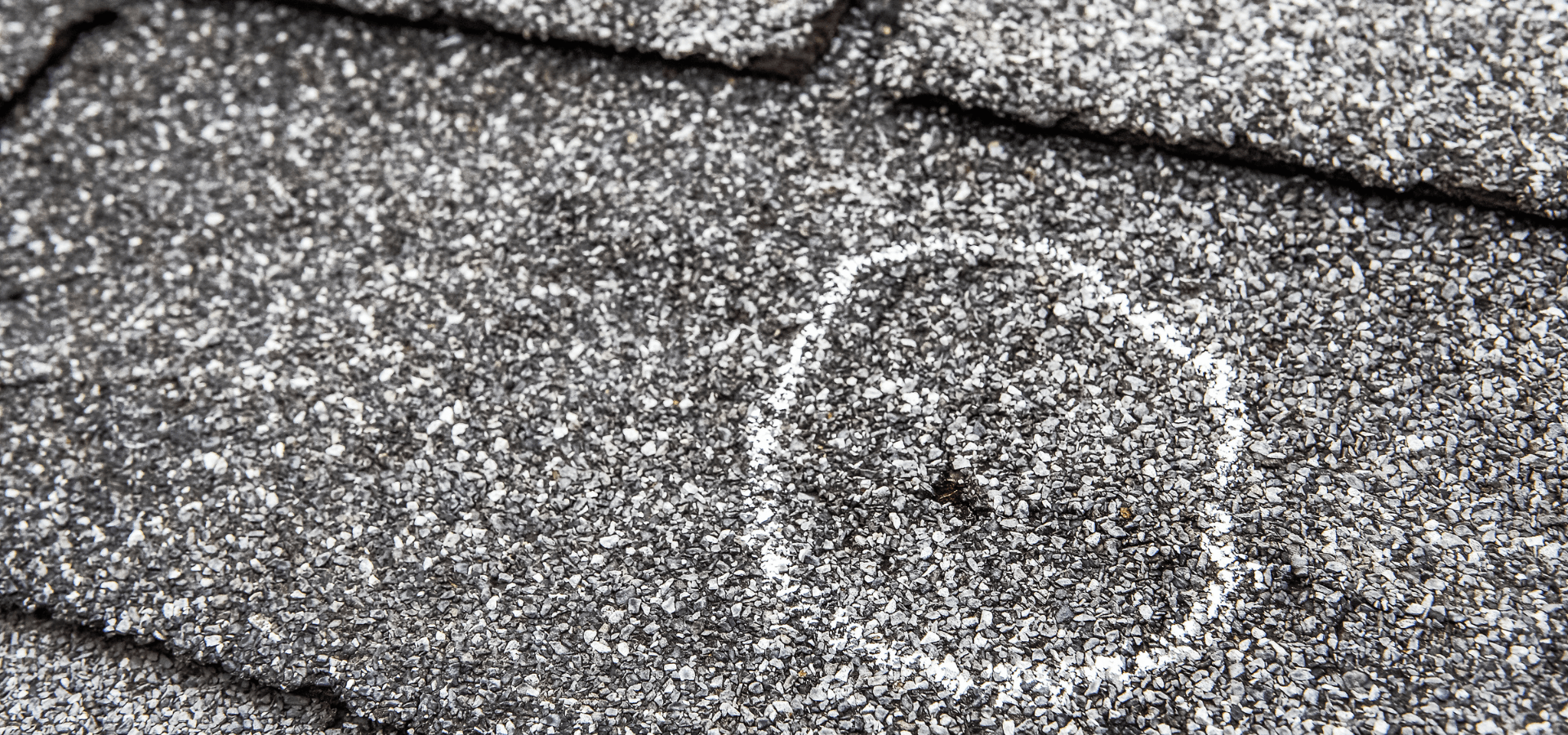 Asphalt shingles with hail damage being inspected for a potential roof replacement project
