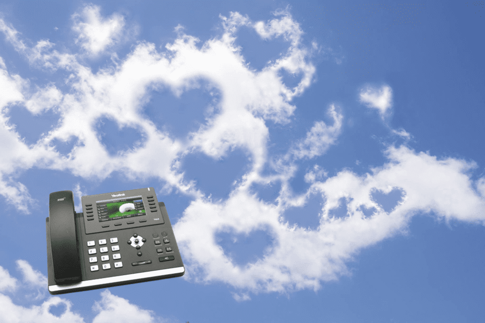 Black office phone floating against a blue sky with heart-shaped clouds.