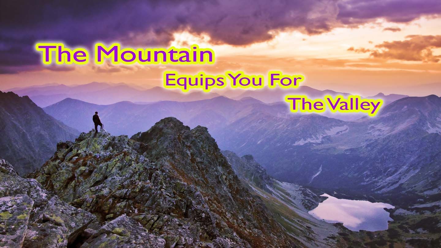 A person stands atop a mountain, overlooking a valley with a lake. Text reads, 
