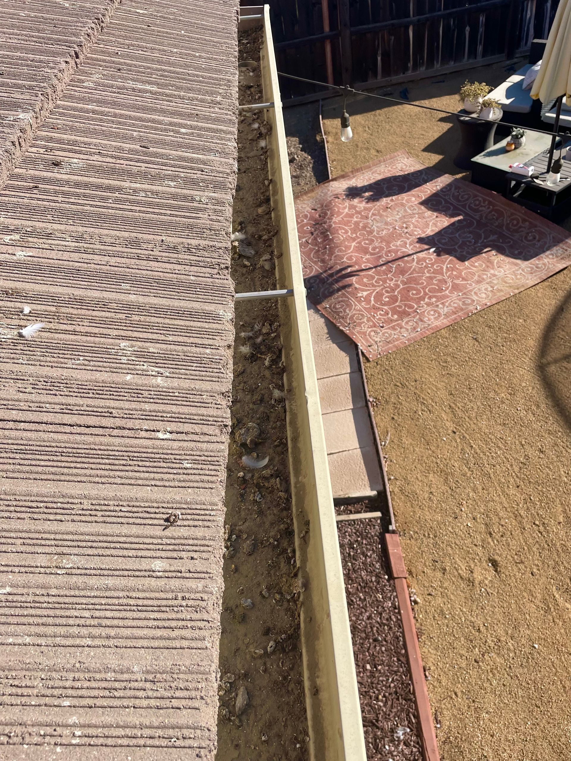 A drain is being installed on the side of a brick wall.