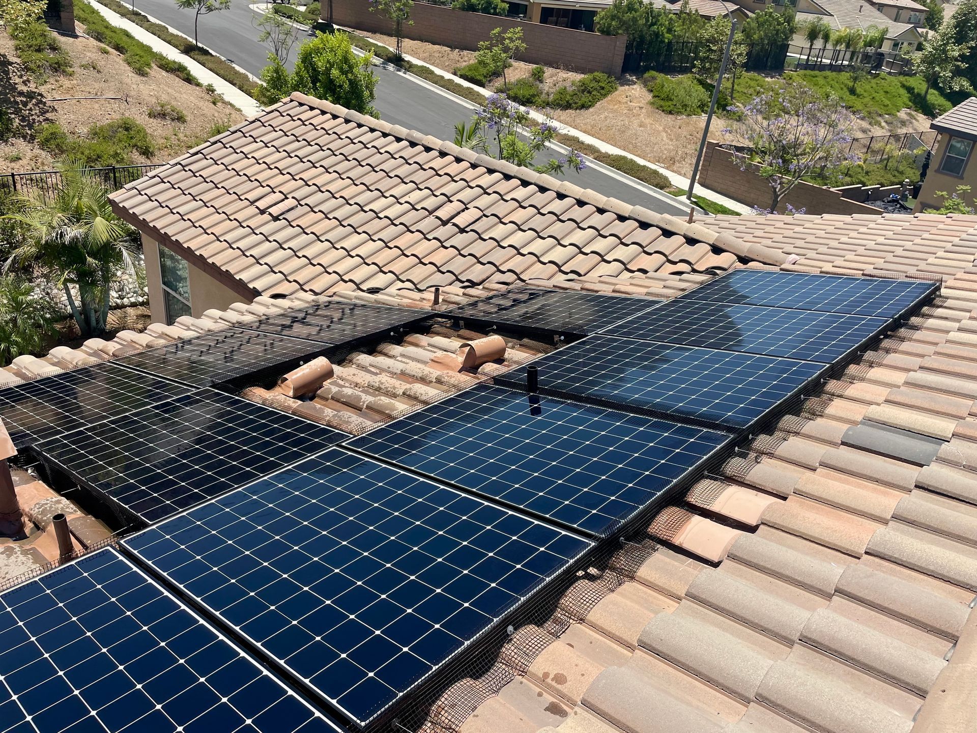 A row of solar panels are sitting on top of a tiled roof.