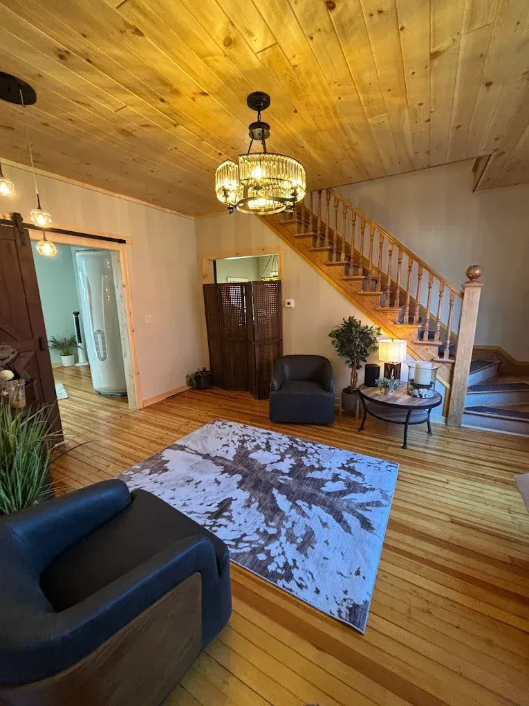 Living room with wooden floors and ceiling, staircase, and a patterned rug.