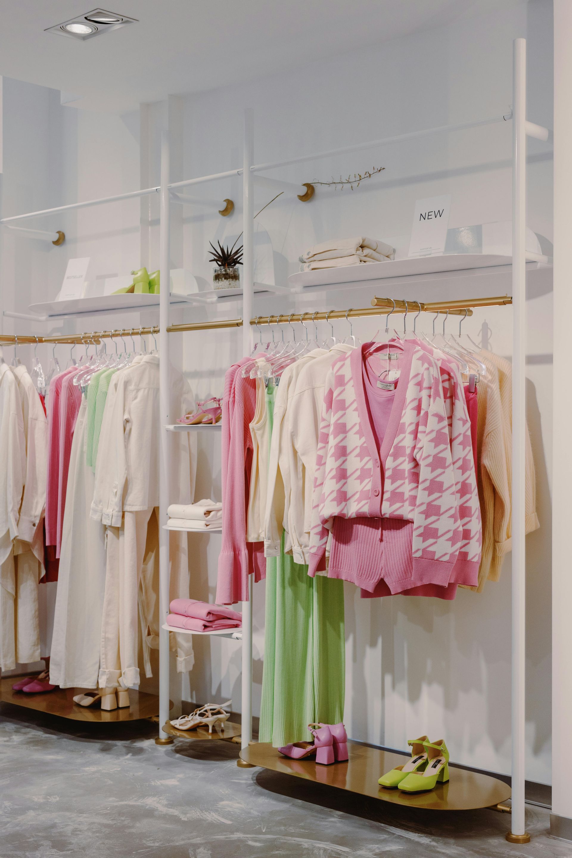 Clothing store interior with pastel-colored clothes on display racks.