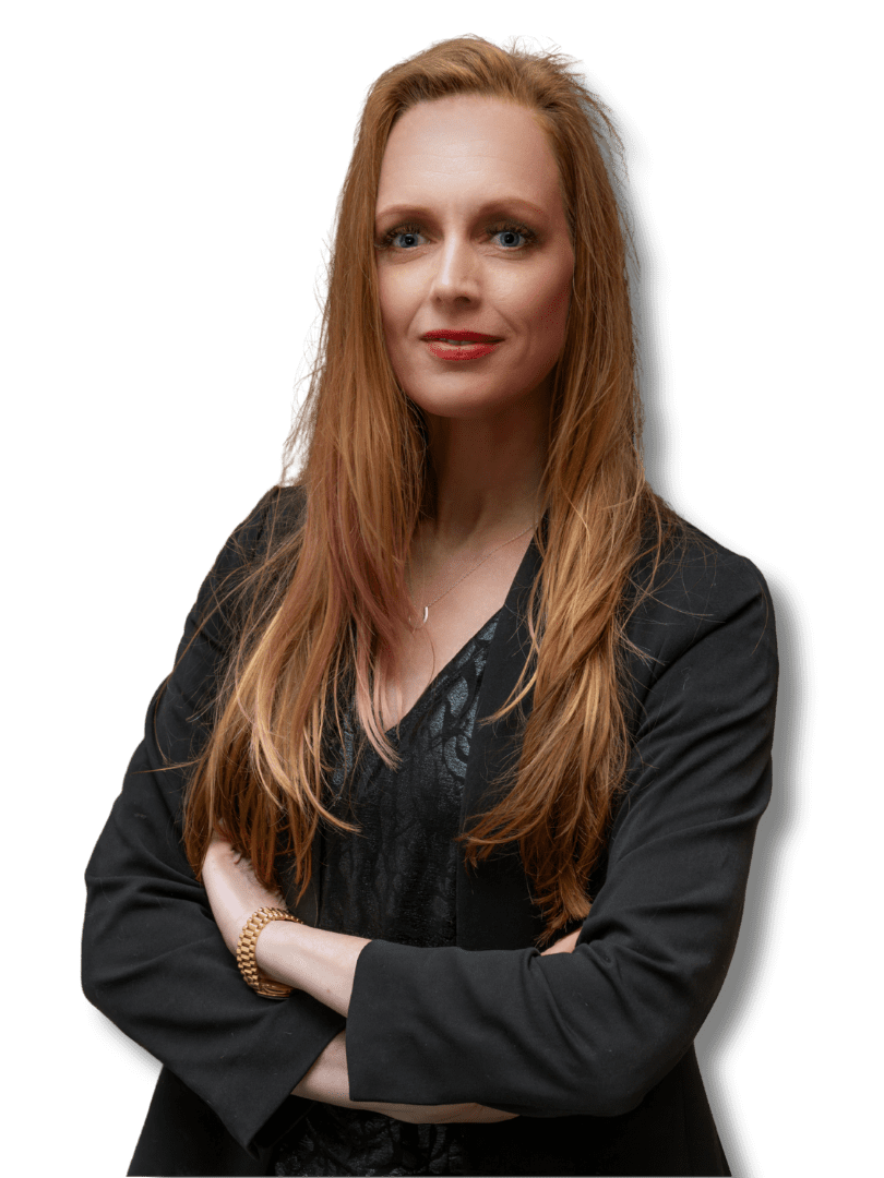 Man in navy suit and pink tie smiles in a library, bookshelves in the background.