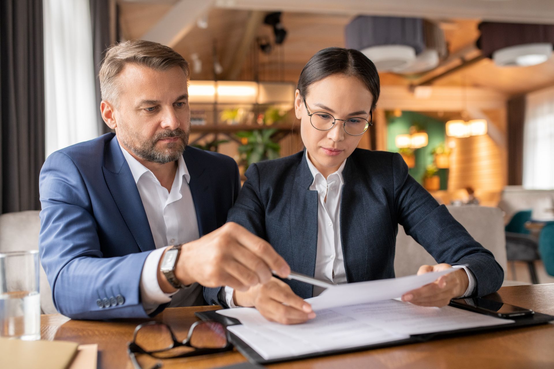 Two professionals reviewing paperwork at a table in a restaurant.