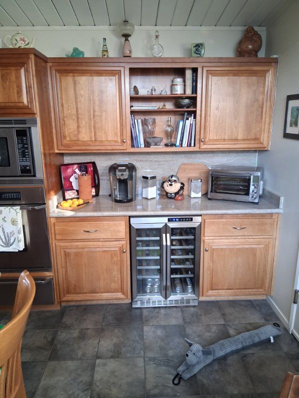 Kitchen wall with wood cabinets, countertop appliances, and a small wine fridge underneath.
