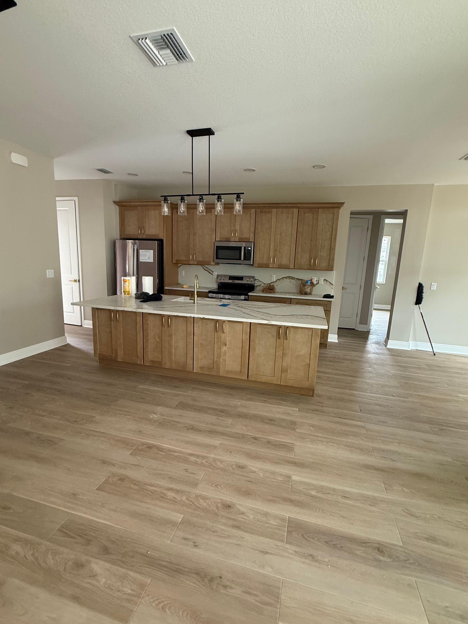 Open-concept kitchen with wood cabinets, large island, and light wood flooring in a modern home