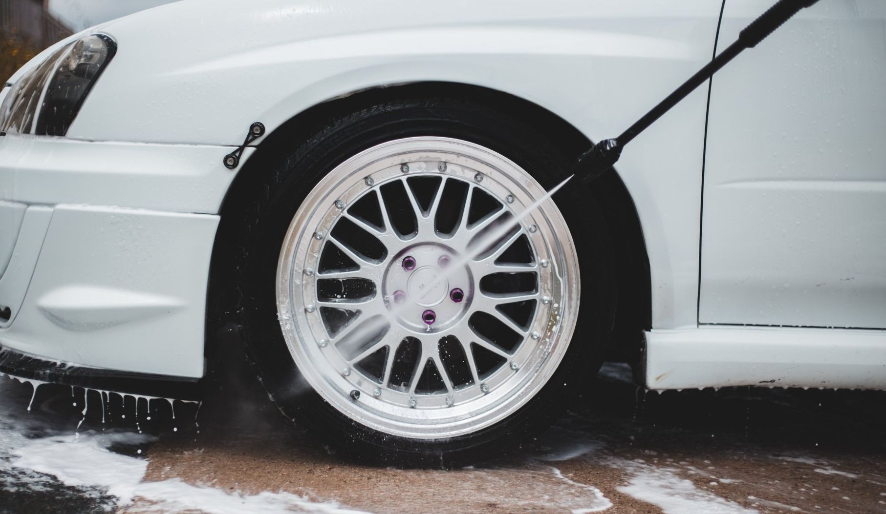 using a pressure washer to clean a cars exterior and tires 