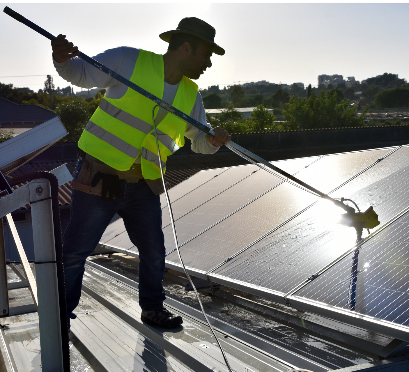 man on a rooftop cleaning solar panels for a commercial building in Houston Texas