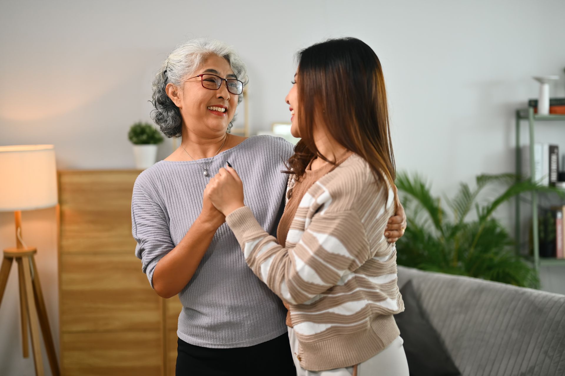 Two people smiling and holding hands in a bright, modern living room.