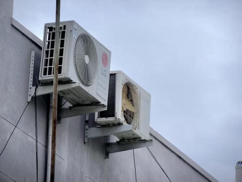 An old and a new HVAC system mounted to the top of a building