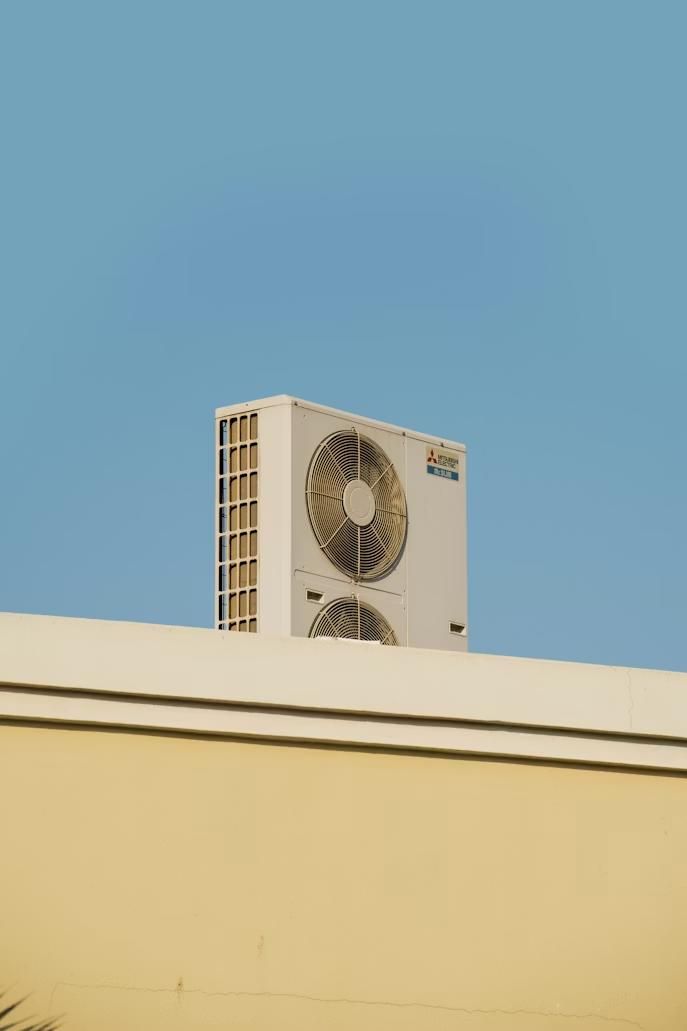 An air conditioning unit placed on top of a yellow wall