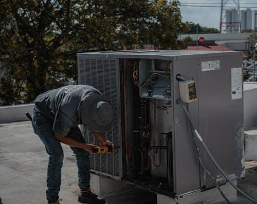 A professional repairs an AC unit.