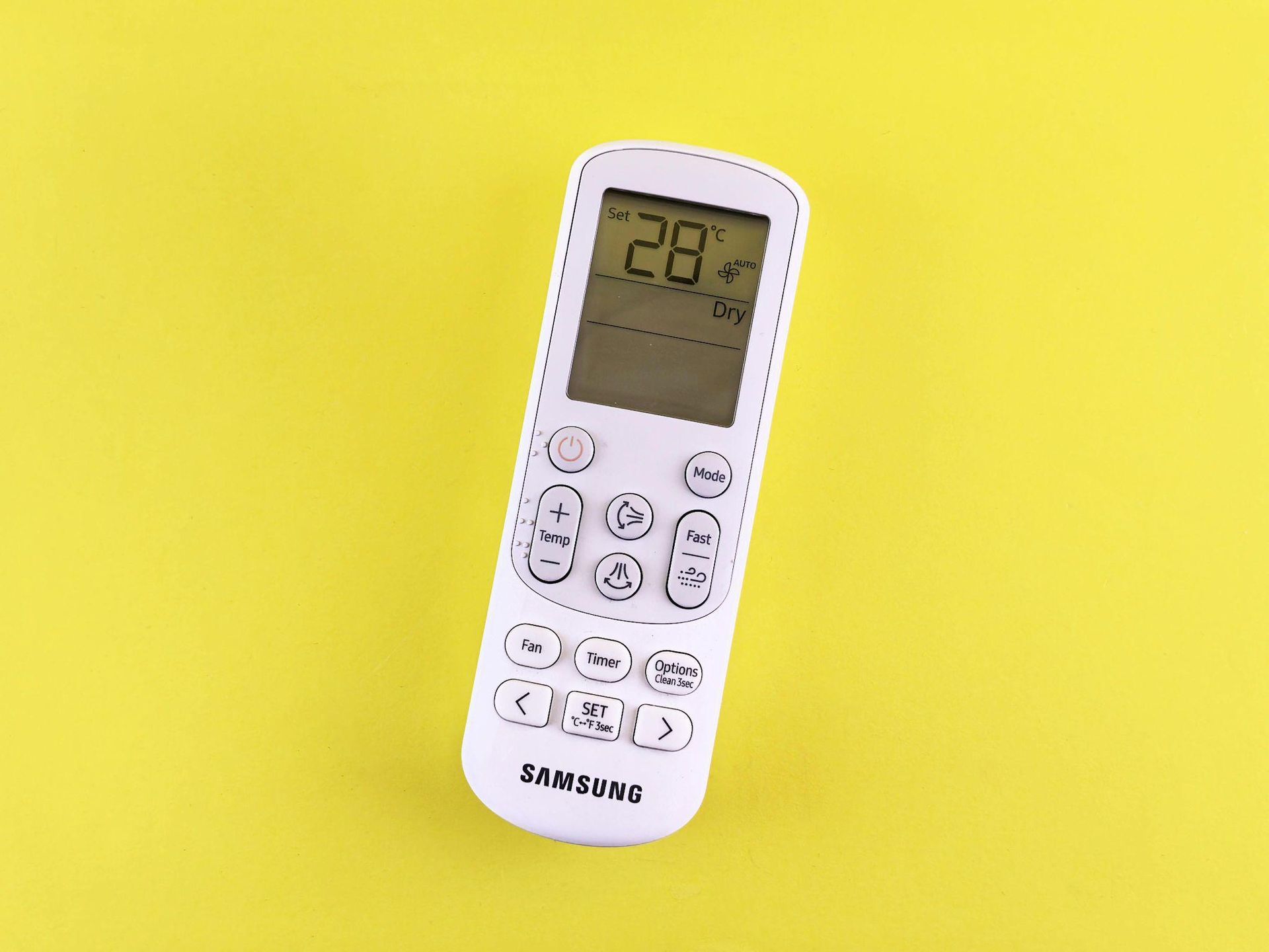 This photo shows an air conditioner remote against a yellow background.