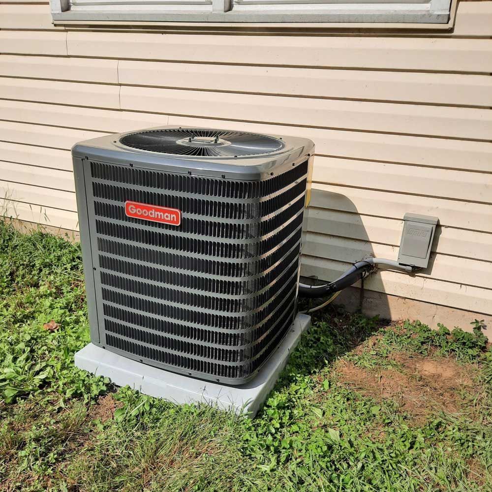 Goodman HVAC system placed on a concrete pad outside a home.