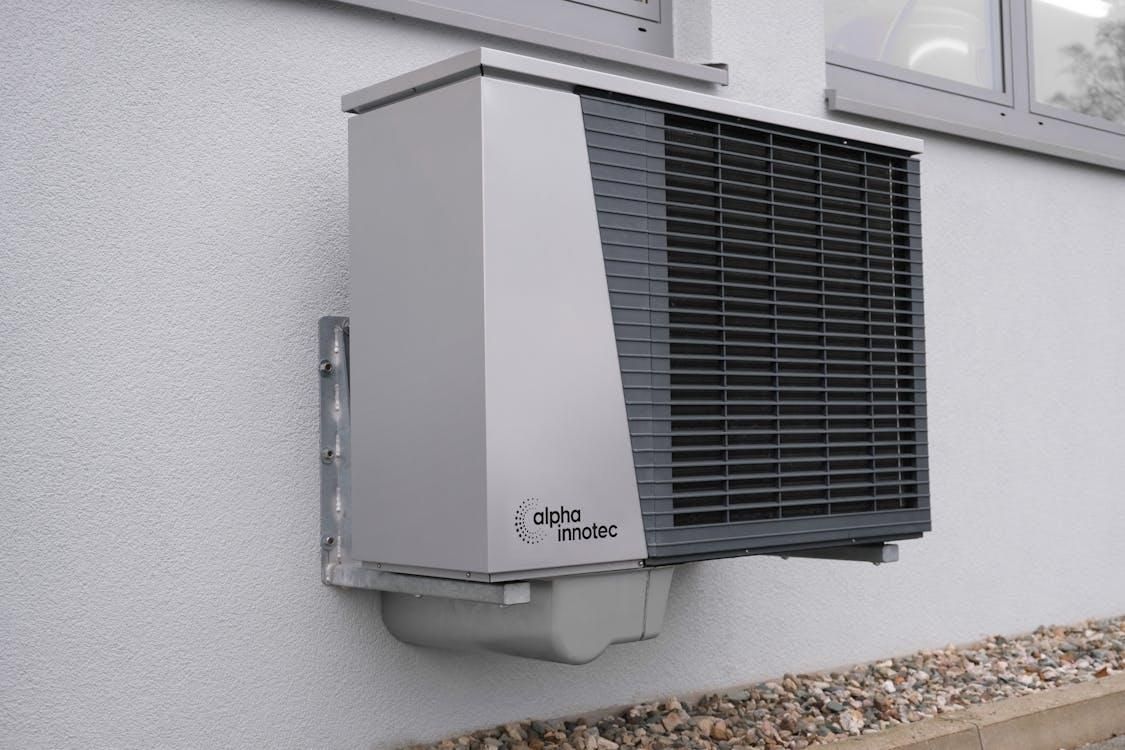 Outdoor HVAC unit mounted on a residential wall for efficient heating and cooling.