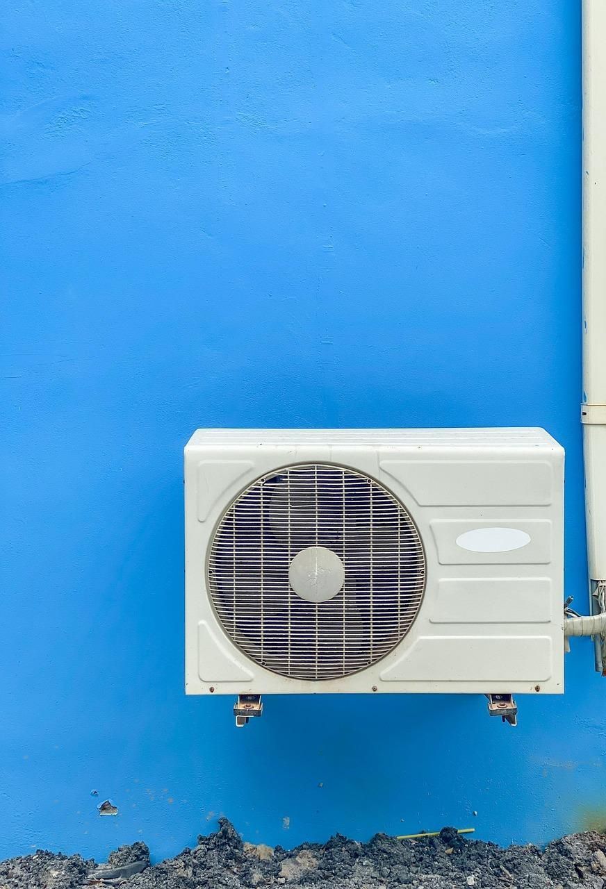 An HVAC outdoor unit mounted on a blue wall.