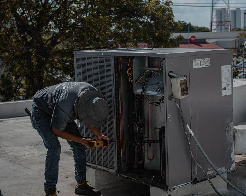 a man working on an air conditioning unit.