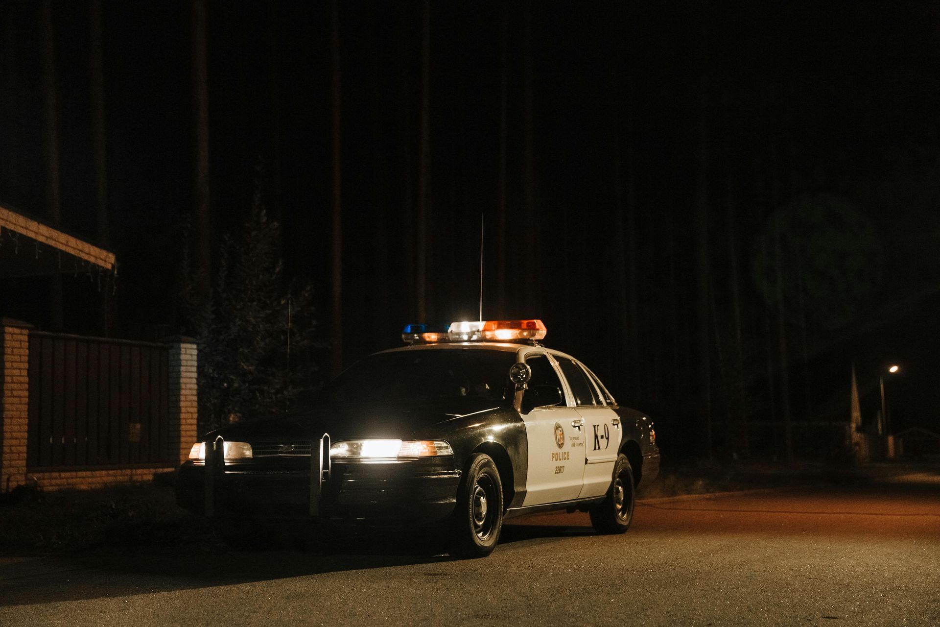 A police car is parked on the side of the road at night