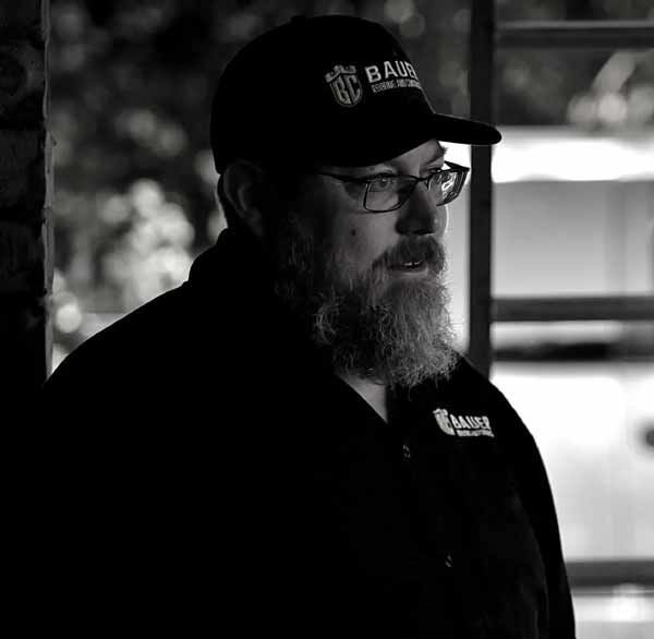 A black and white photo of a man with a beard wearing a hat and glasses.