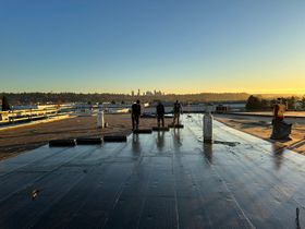 a group of workers standing on a roof with a city skyline in the background