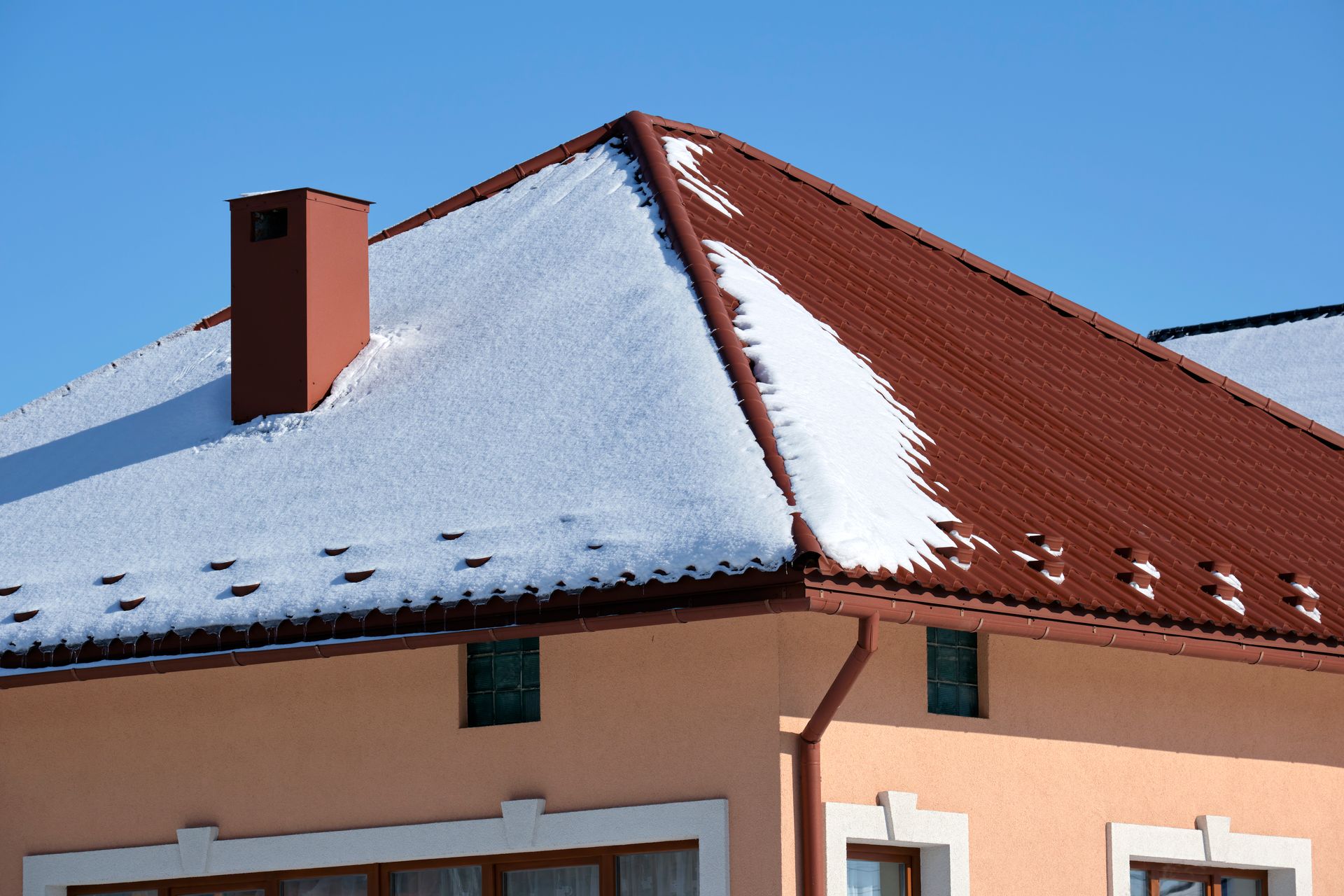 A house with snow on the roof and a chimney