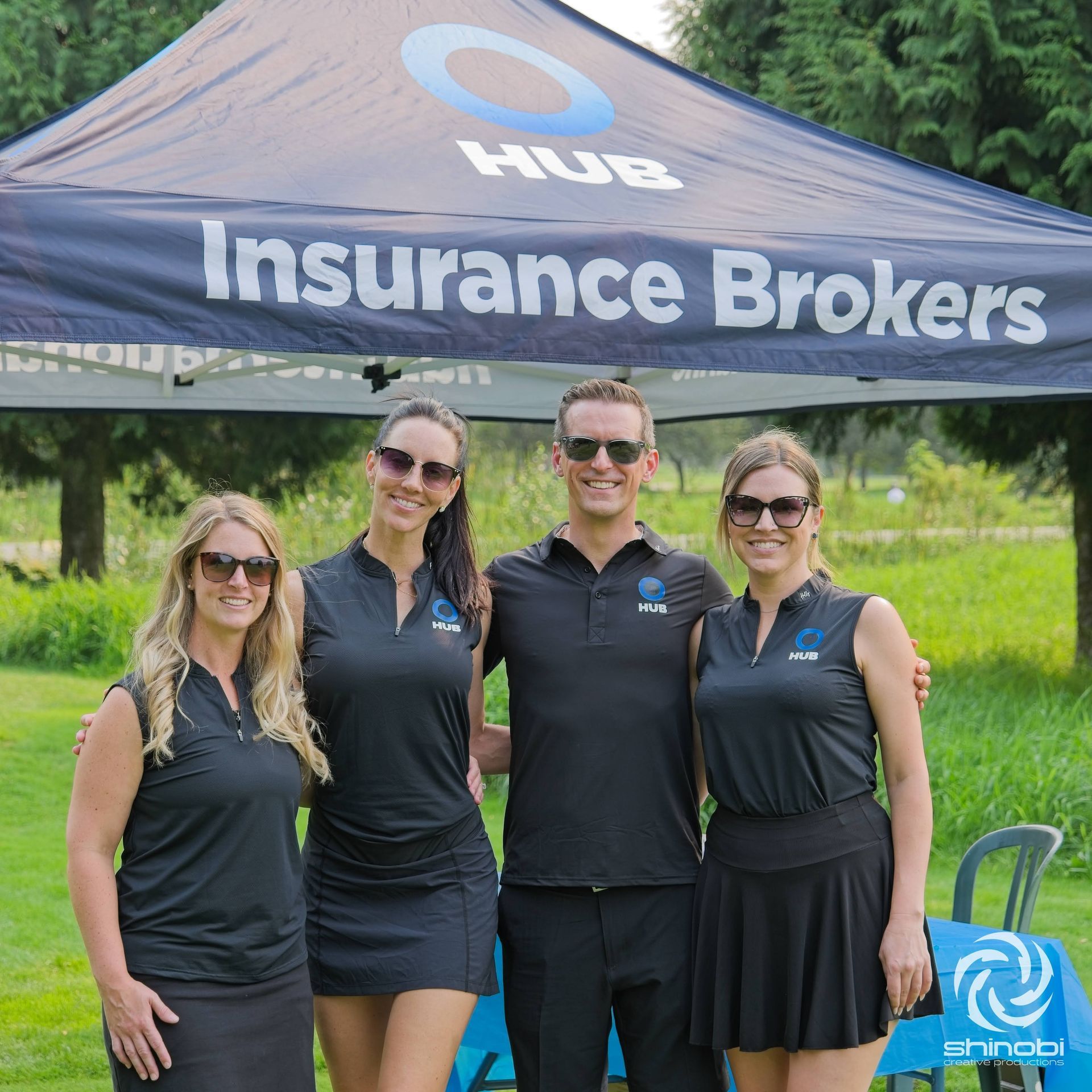 A group of people standing under an insurance brokers tent