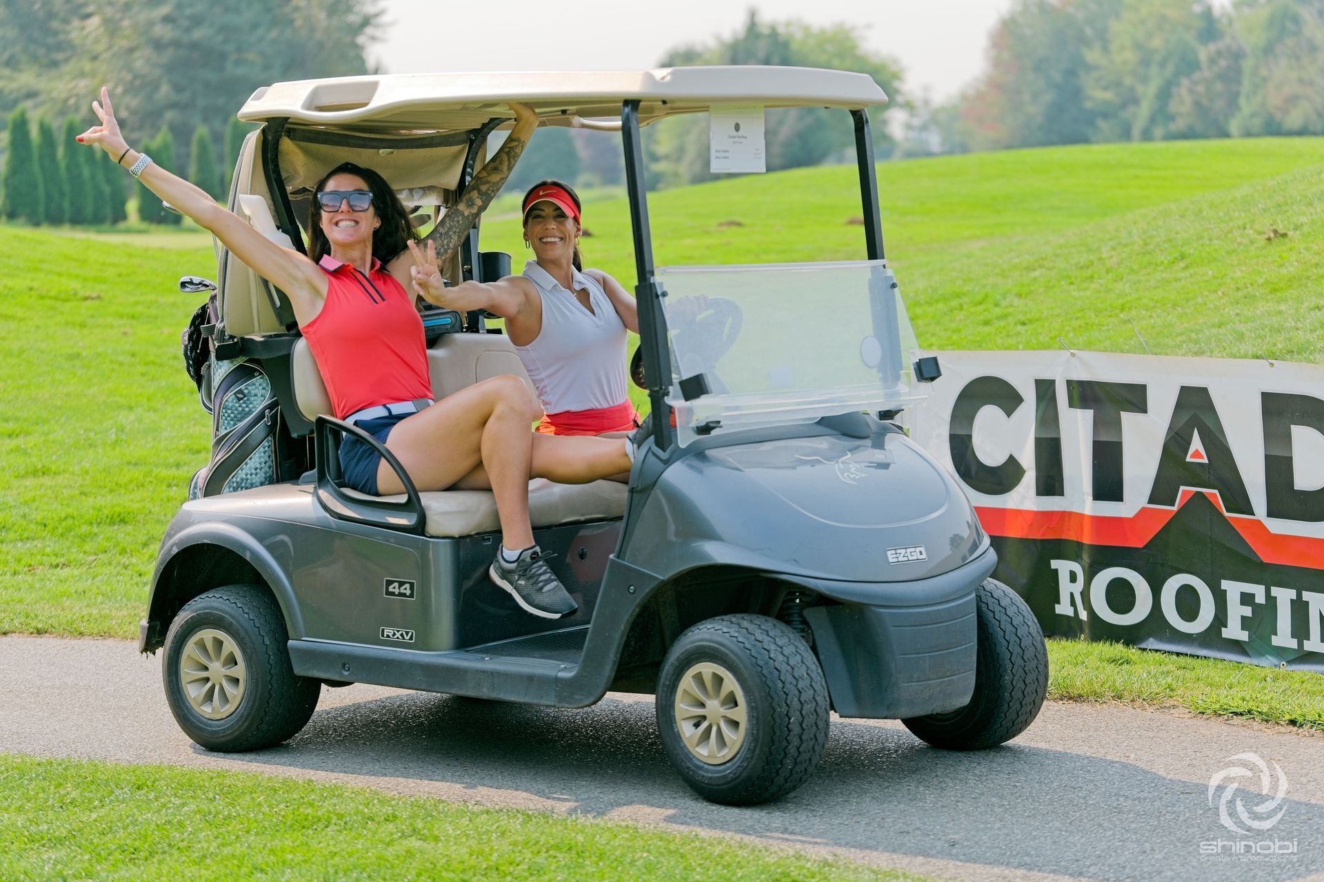 Two women are sitting in a golf cart on a golf course.