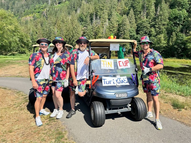 A group of people are standing next to a golf cart.