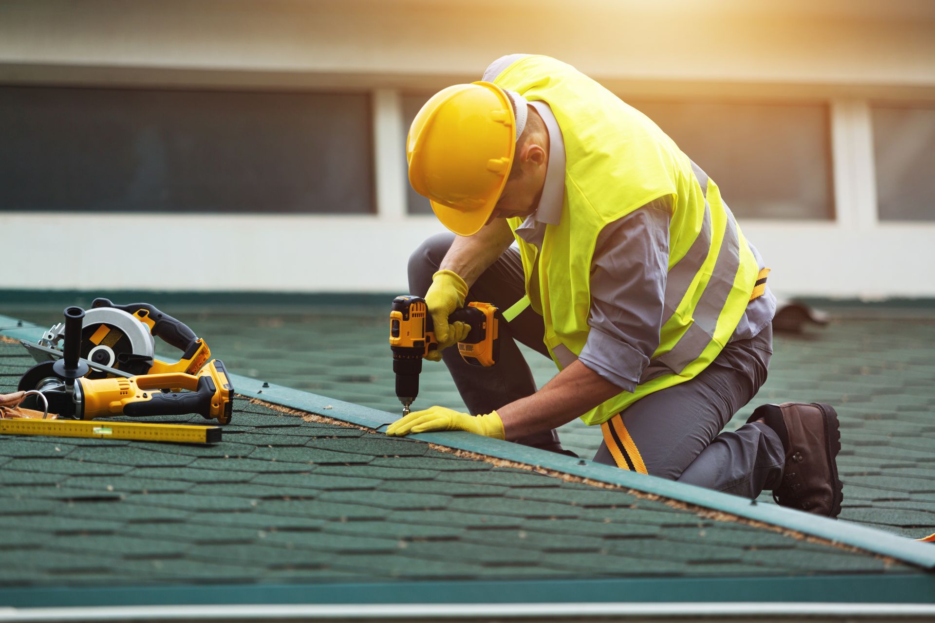A construction worker is working on a roof with a drill.