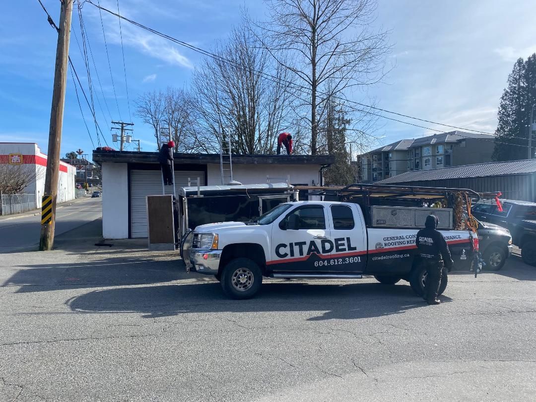 A white truck with the word citadel on the side is parked in front of a building.