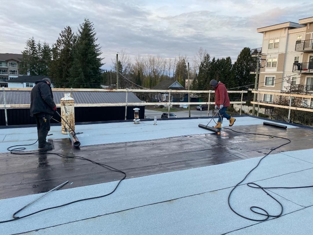 Two men are working on a roof in the rain.