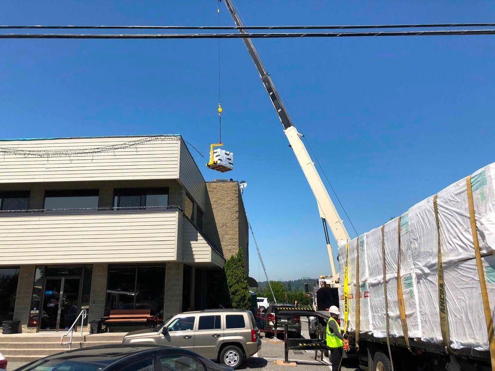 A crane is lifting a large object in front of a building.