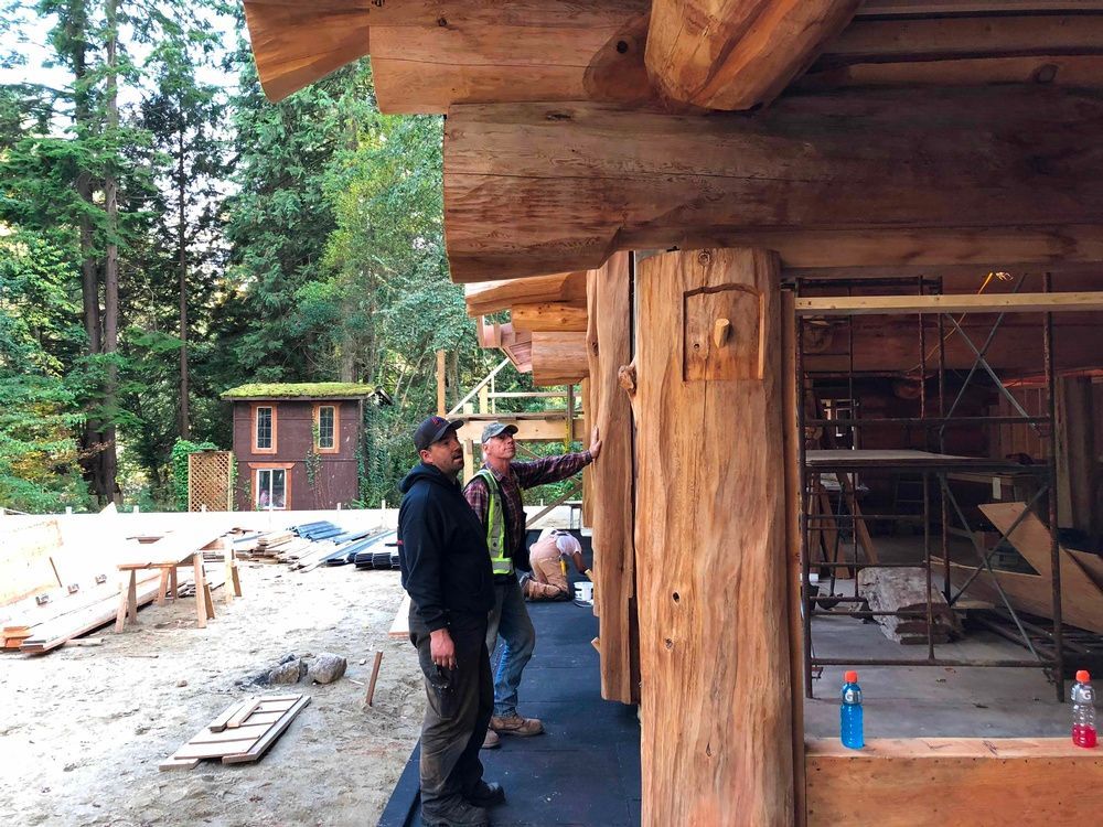 Two men are standing in front of a wooden building.