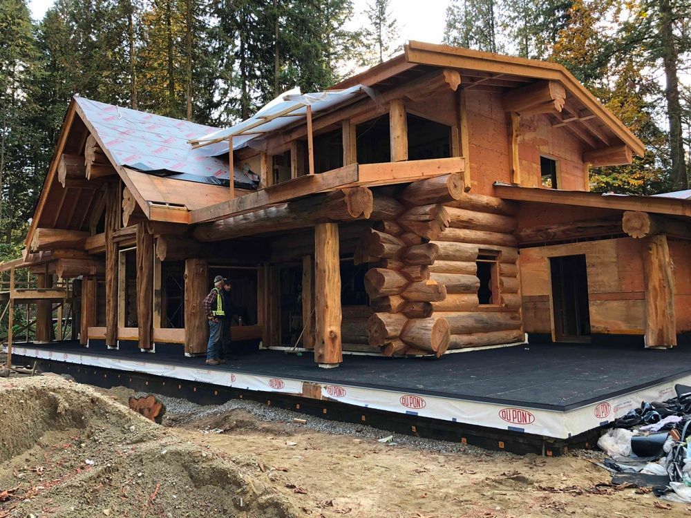 A large log cabin is being built in the middle of a forest.