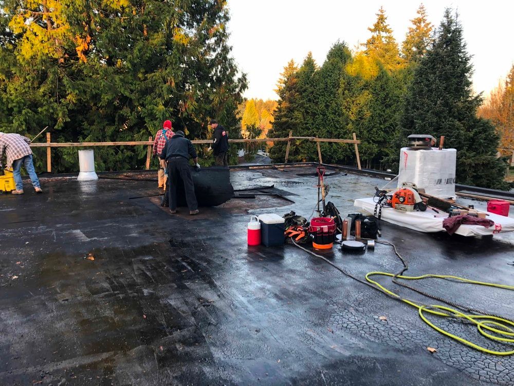 A group of people are working on a roof in the rain.